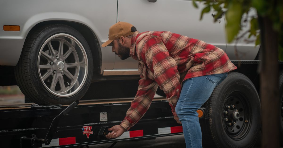 Man leaning down to adjust trailer in preparation for winter. The trailer has had regular maintenance. " width="1200" height="630