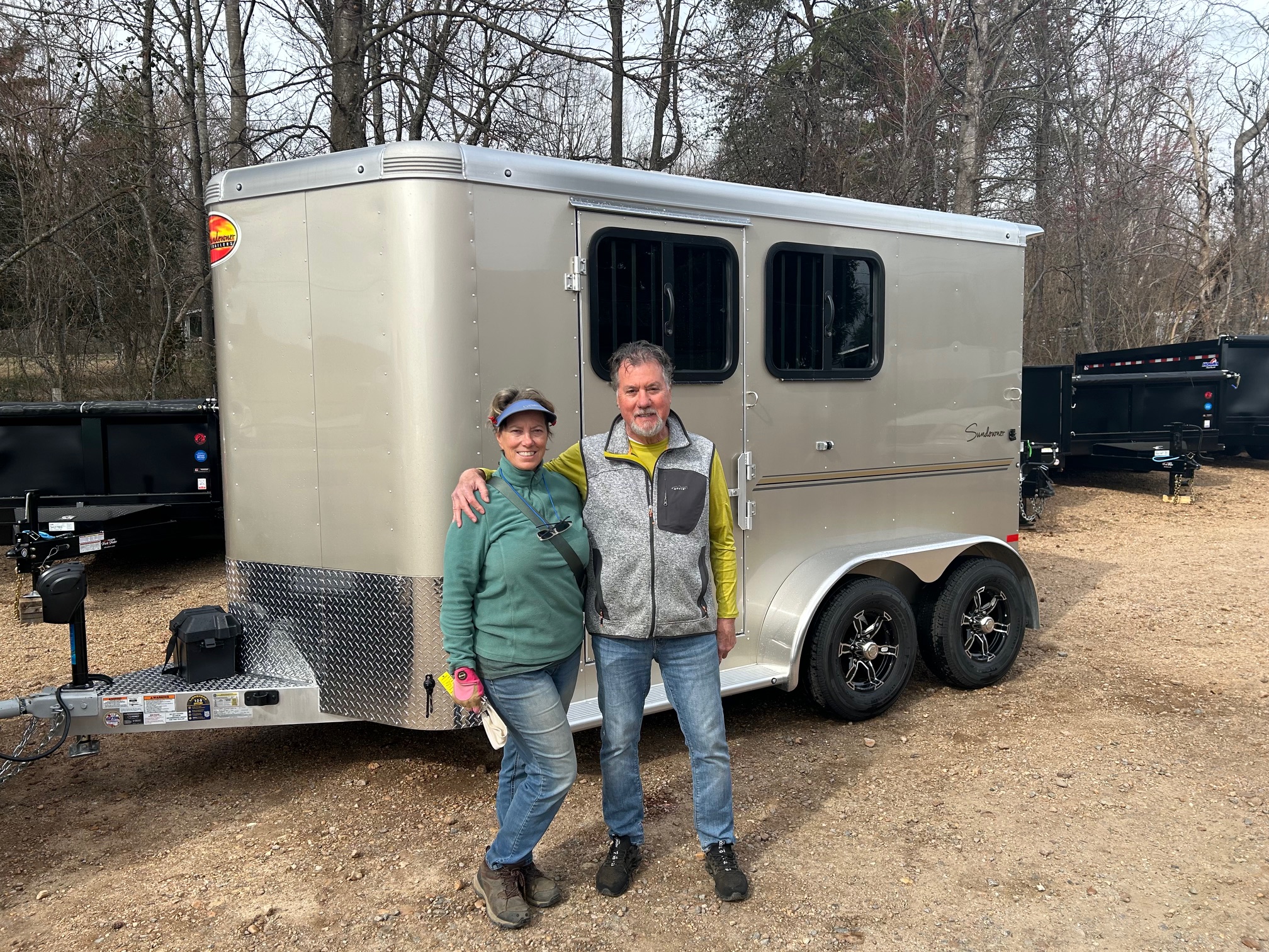 couple in front of sundowner charter two horse bumper pull trailer" width="800" height="600
